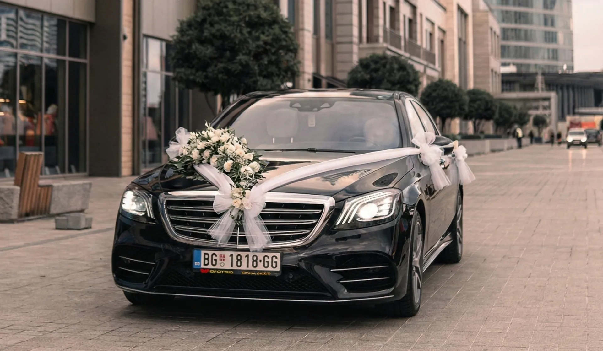 Elegant Wedding Luxury Sedan Decorated with White Roses lack luxury sedan decorated with elegant white floral arrangements and ribbons on the hood for a wedding ceremony.