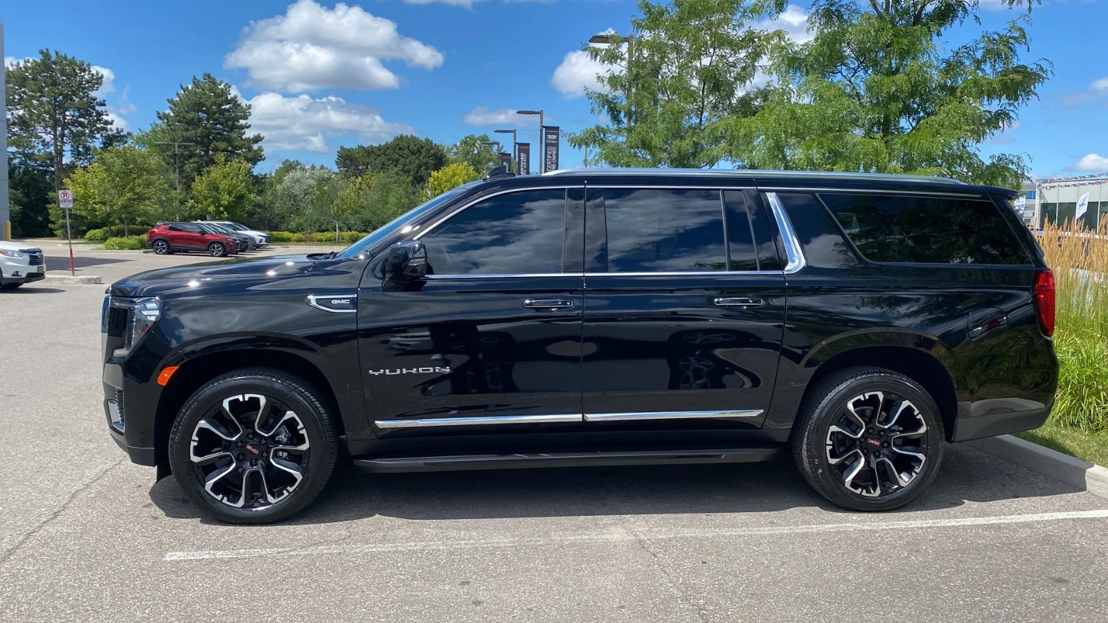 Luxury Black GMC Yukon XL Executive SUV Fleet Vehicle Side profile view of a sleek black GMC Yukon XL luxury SUV parked outdoors under a blue sky, ideal for executive limousine and chauffeur services in Ontario.