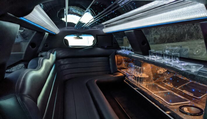 A customer reviewing limo booking details on a tablet beside a luxury limousine