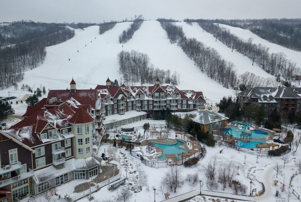 A panoramic view of Blue Mountain Ski Resort with snowy slopes and the nearby Scenic Grottoes surrounded by natural landscapes.