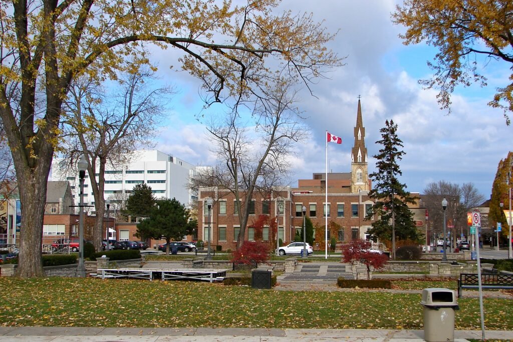 Downtown Oshawa with historic buildings, trees with autumn leaves, and the Canadian flag flying in the town square