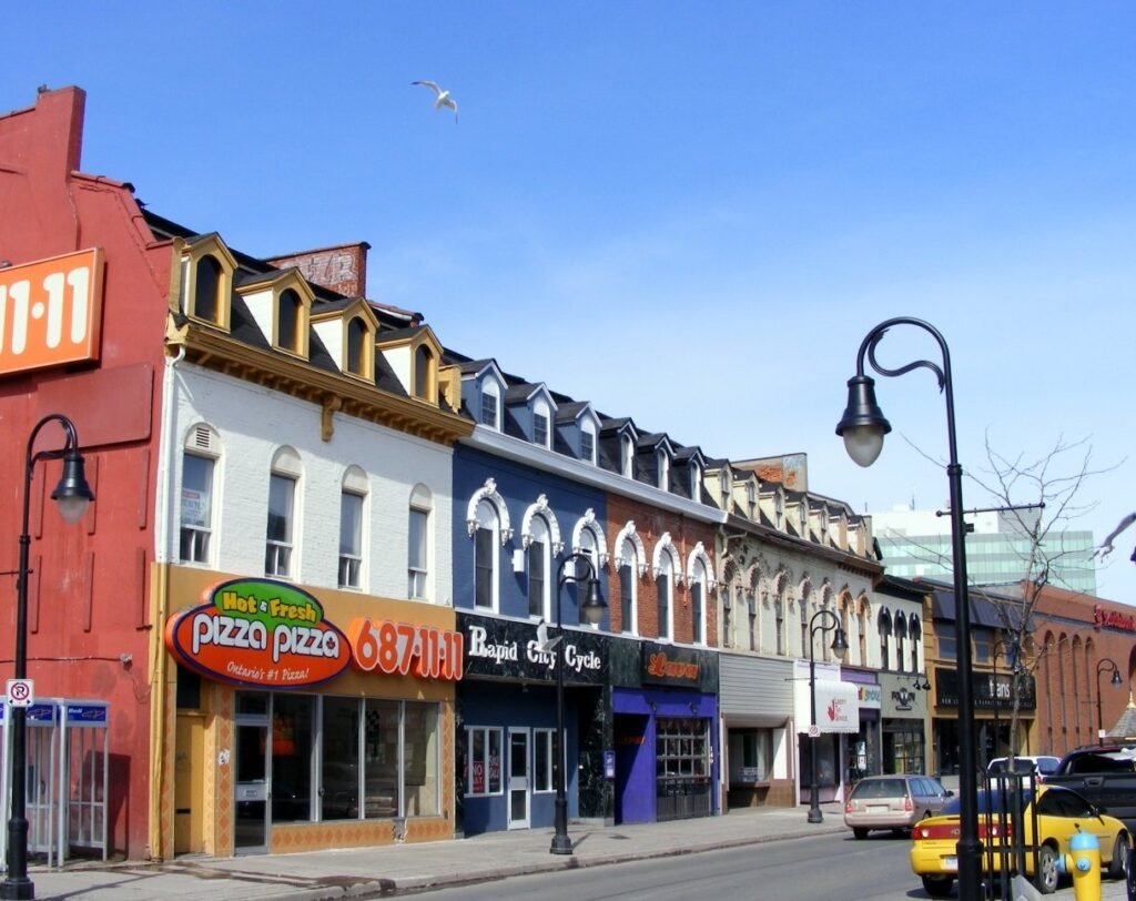 Row of colorful historic storefronts with shops and restaurants along a sunny city street.