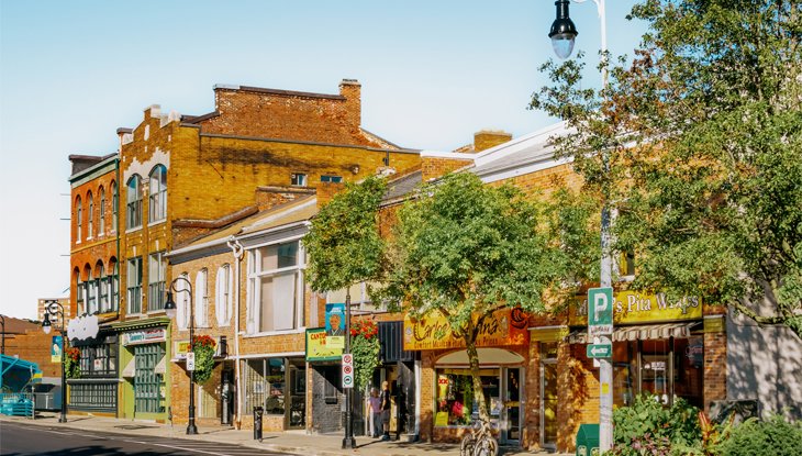Historic brick storefronts and local shops along a tree-lined street in downtown St. Catharines, Ontario.